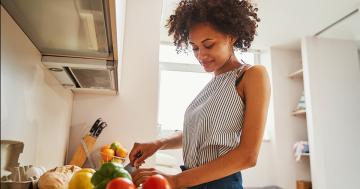 Woman cutting vegetables in her kitchen, representing how reproductive health and the environment connect at home.