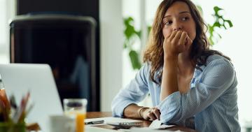 Woman sitting at her desk at work, debating how to cope with a pregnancy scare.