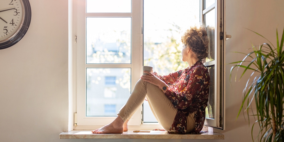 Woman sitting by the window contemplating what to do during 2-week wait