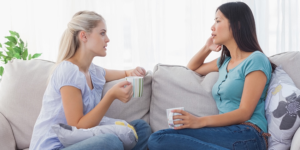 two women sitting on sofa chatting